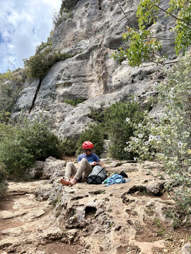 Arrampicatore che si prepara alla base di una falesia, su una piattaforma di roccia piana